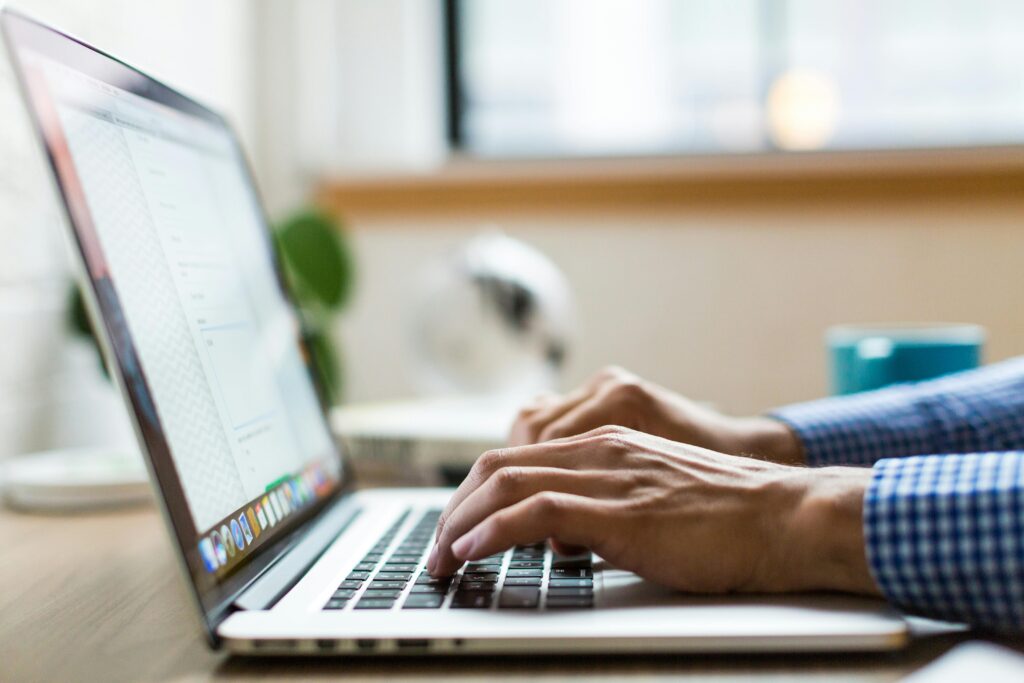 Home Close-up of adult typing on laptop in bright, modern office.
